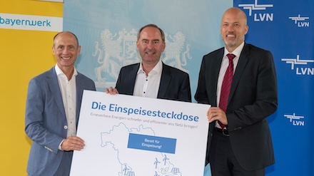 Bayernwerk-Vorstandsvorsitzender Egon Leo Westphal (rechts) und LEW-Vorstand Christian Barr (links) stellen dem bayerischen Wirtschaftsminister Hubert Aiwanger die Einspeisesteckdose vor.