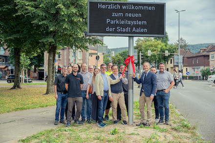 Aalens Oberbürgermeister Frederick Brütting (3.v.re.) freut sich gemeinsam mit Erstem Bürgermeister Wolfgang Steidle (5.v.re.), Mitgliedern des Gemeinderats sowie Projektbeteiligten der Stadtverwaltung über den Start des neuen Parkleitsystems. 